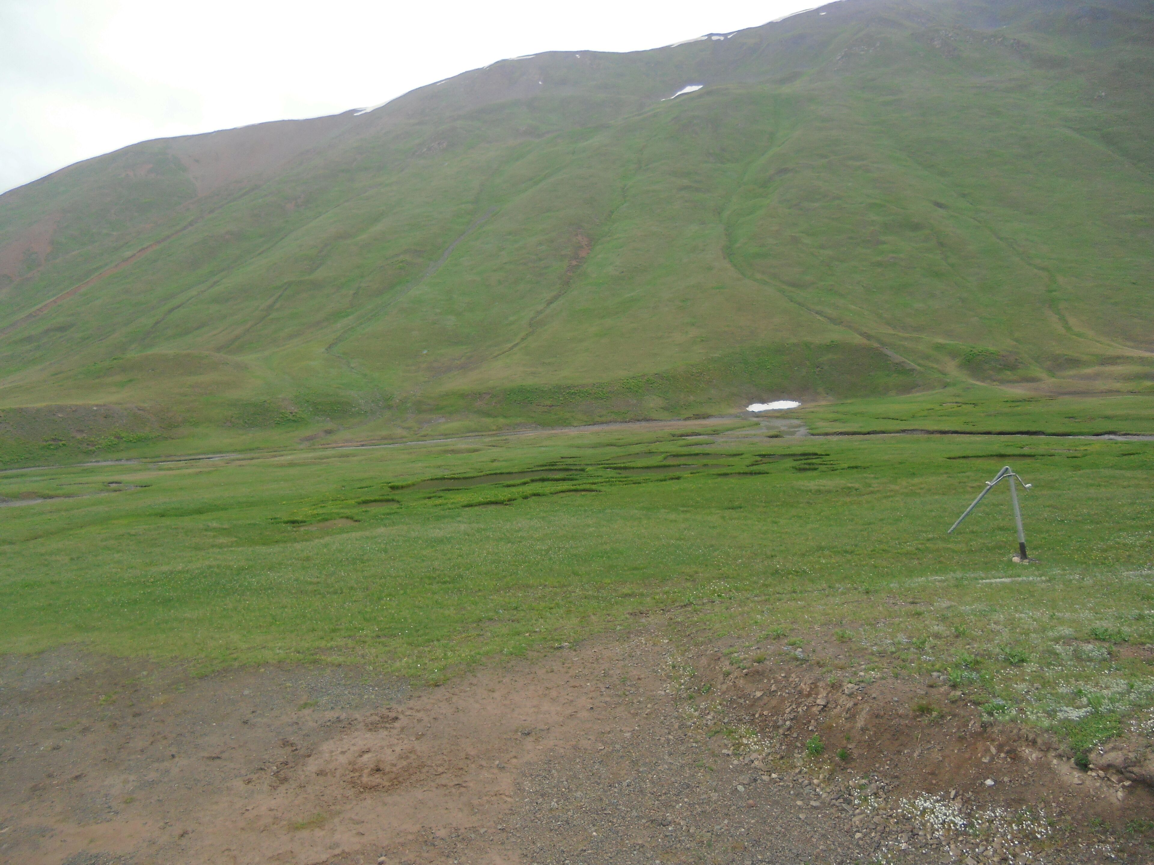 Un paisaje montañoso con un pequeño edificio blanco y un trípode en primer plano.