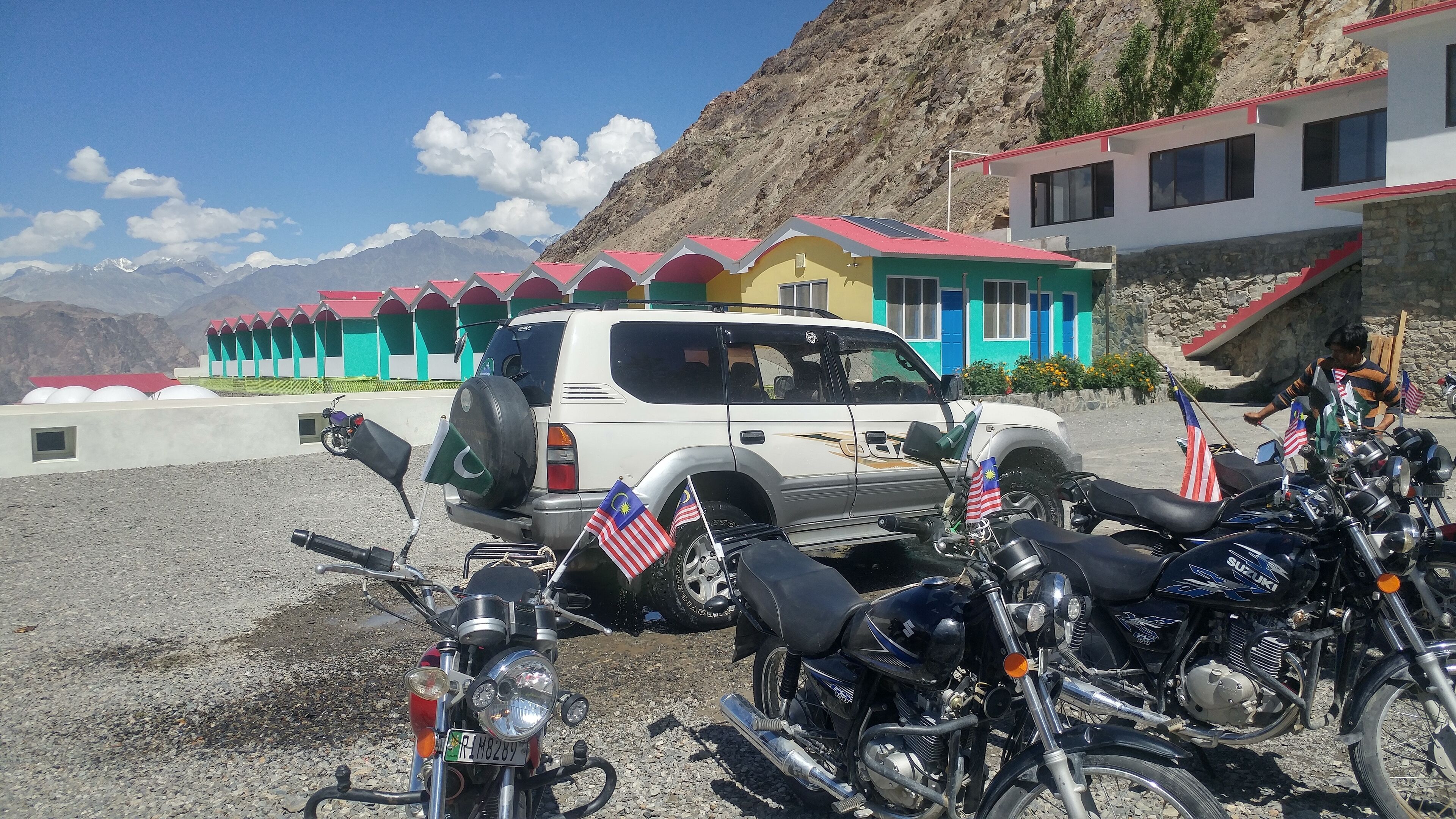 Un estacionamiento con varias motocicletas y un SUV blanco.