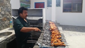 Una persona asando pollo en una parrilla de carbón al aire libre.