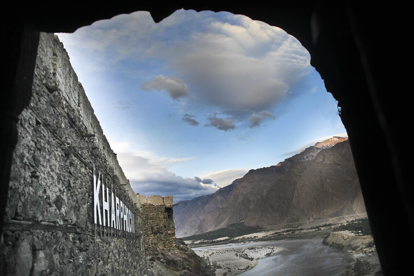 A view through a cave opening with a stone wall labeled "KARAGH".