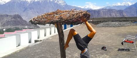 A person performing an acrobatic move on a rooftop with a mountainous backdrop.