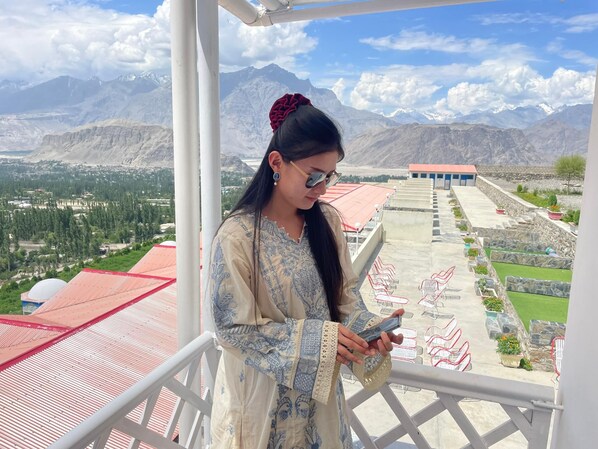 A person on a balcony with a mountainous landscape in the background.