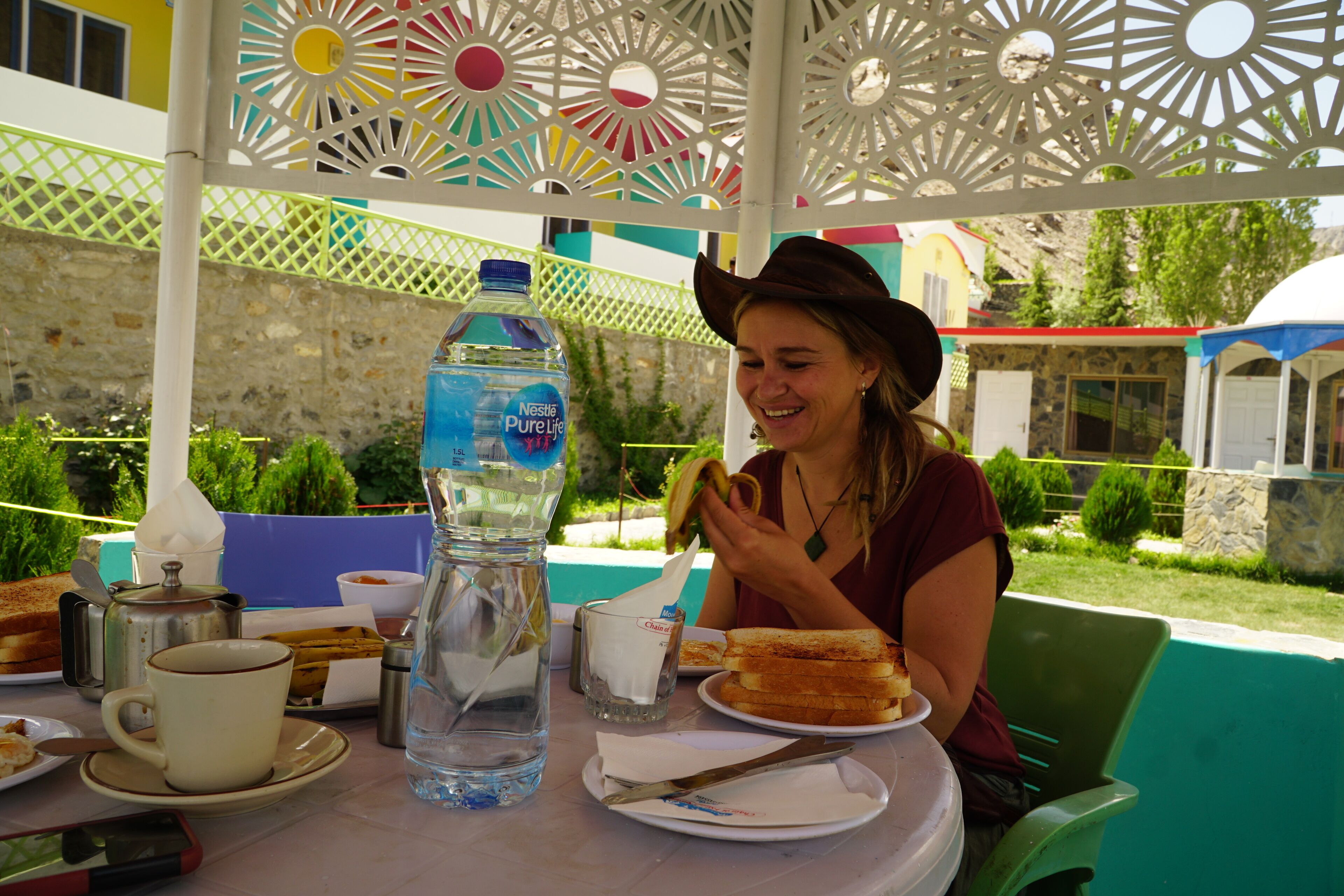 Une table avec une bouteille d’eau, un verre, une assiette contenant de la nourriture et un couteau.