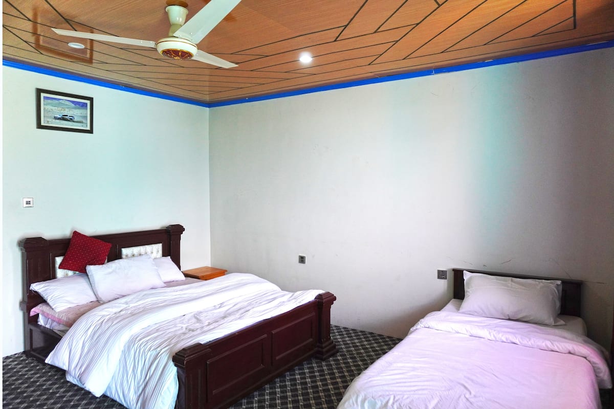 Ein Schlafzimmer mit zwei Betten, einem Deckenventilator und einem gerahmten Bild an der Wand.