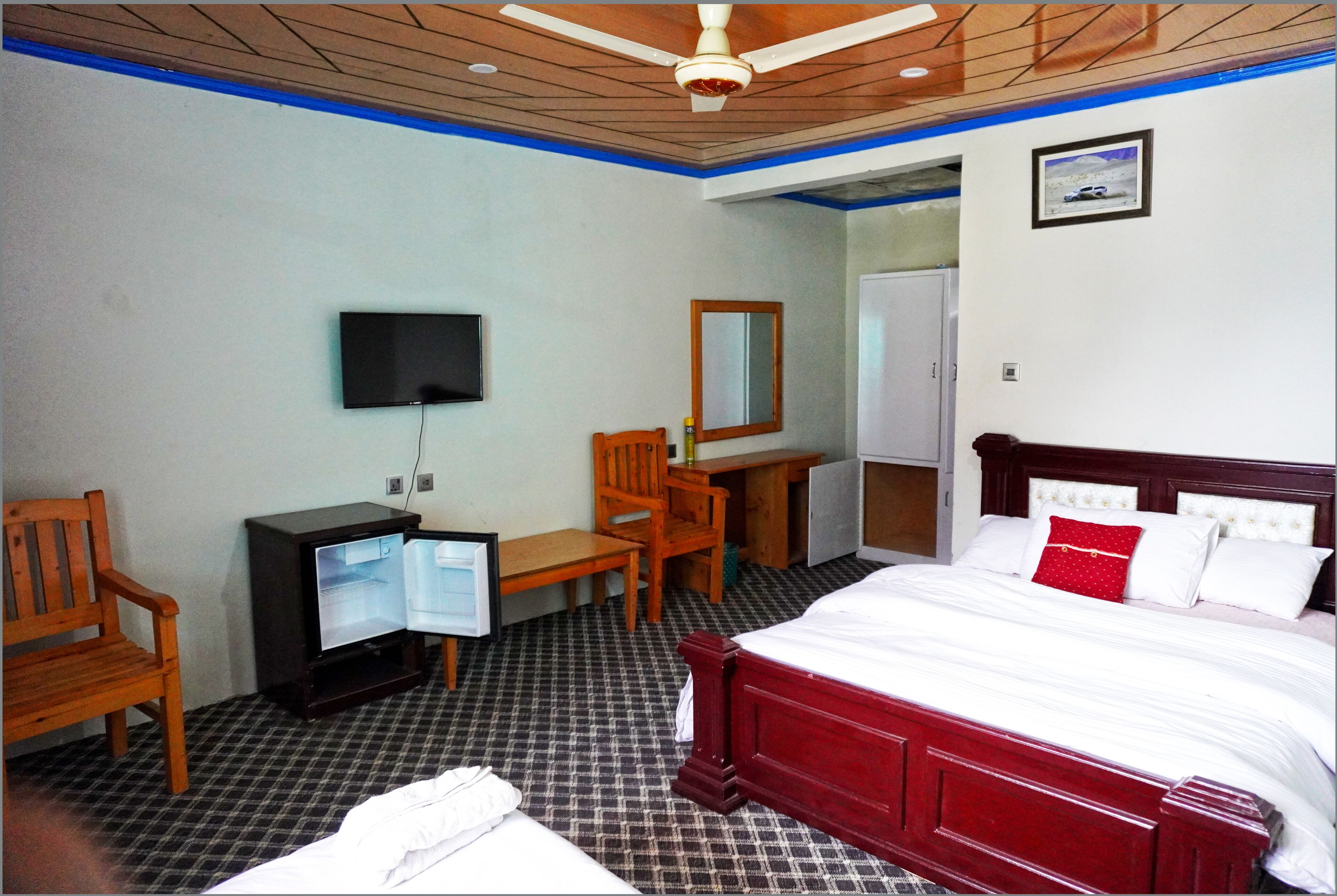 Ein Hotelzimmer mit Bett, Fernseher, Schreibtisch und Stuhl.
