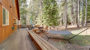 A wooden deck with outdoor furniture, including a table and chairs, surrounded by tall trees. - 4 Mi to Downhill Ski Resort! Spacious Family Haven (Truckee)