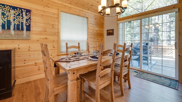A wooden dining table with chairs, a chandelier, and a large window with a view of trees. - 4 Mi to Downhill Ski Resort! Spacious Family Haven (Truckee)