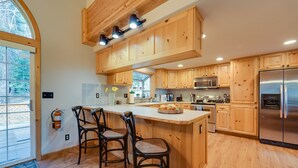 A modern kitchen with wooden cabinets, a stainless steel refrigerator, and a large island with bar stools. - 4 Mi to Downhill Ski Resort! Spacious Family Haven (Truckee)