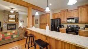 A kitchen with wooden cabinets, a granite countertop, a built-in stove, and a refrigerator.