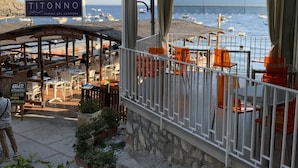 A seaside restaurant with outdoor seating overlooking the beach and marina.