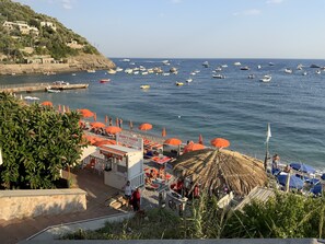 A beach with umbrellas, a sign for 'Mary's Beach', and boats in the water.