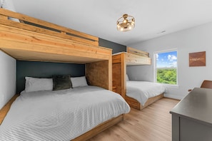 A room with bunk beds, a desk, and a window with a view.