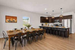 A modern kitchen with dark wooden cabinets, stainless steel appliances, and a dining area with a wooden table and chairs.