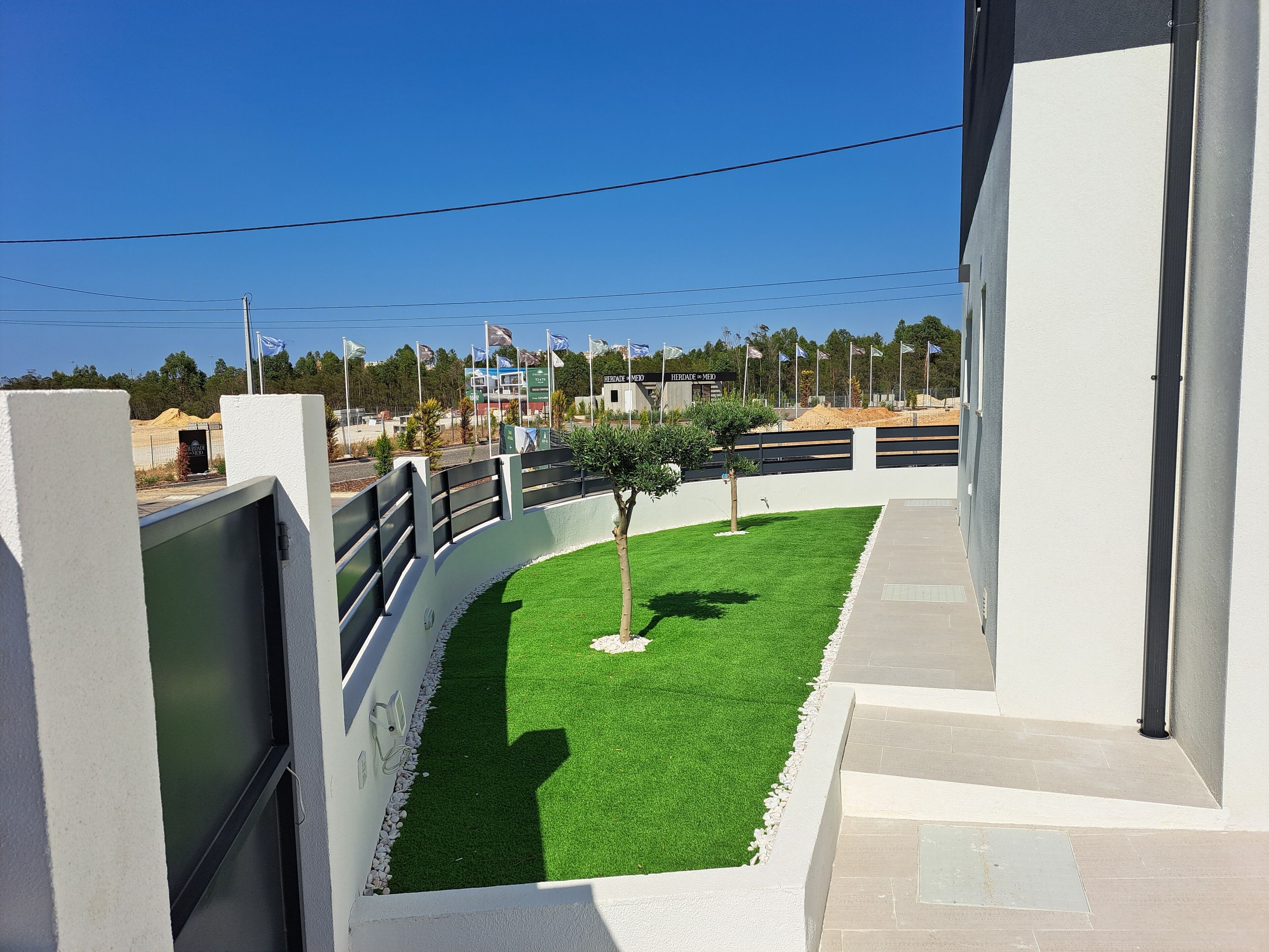 A modern building with a green artificial lawn, a white exterior, and a clear blue sky.