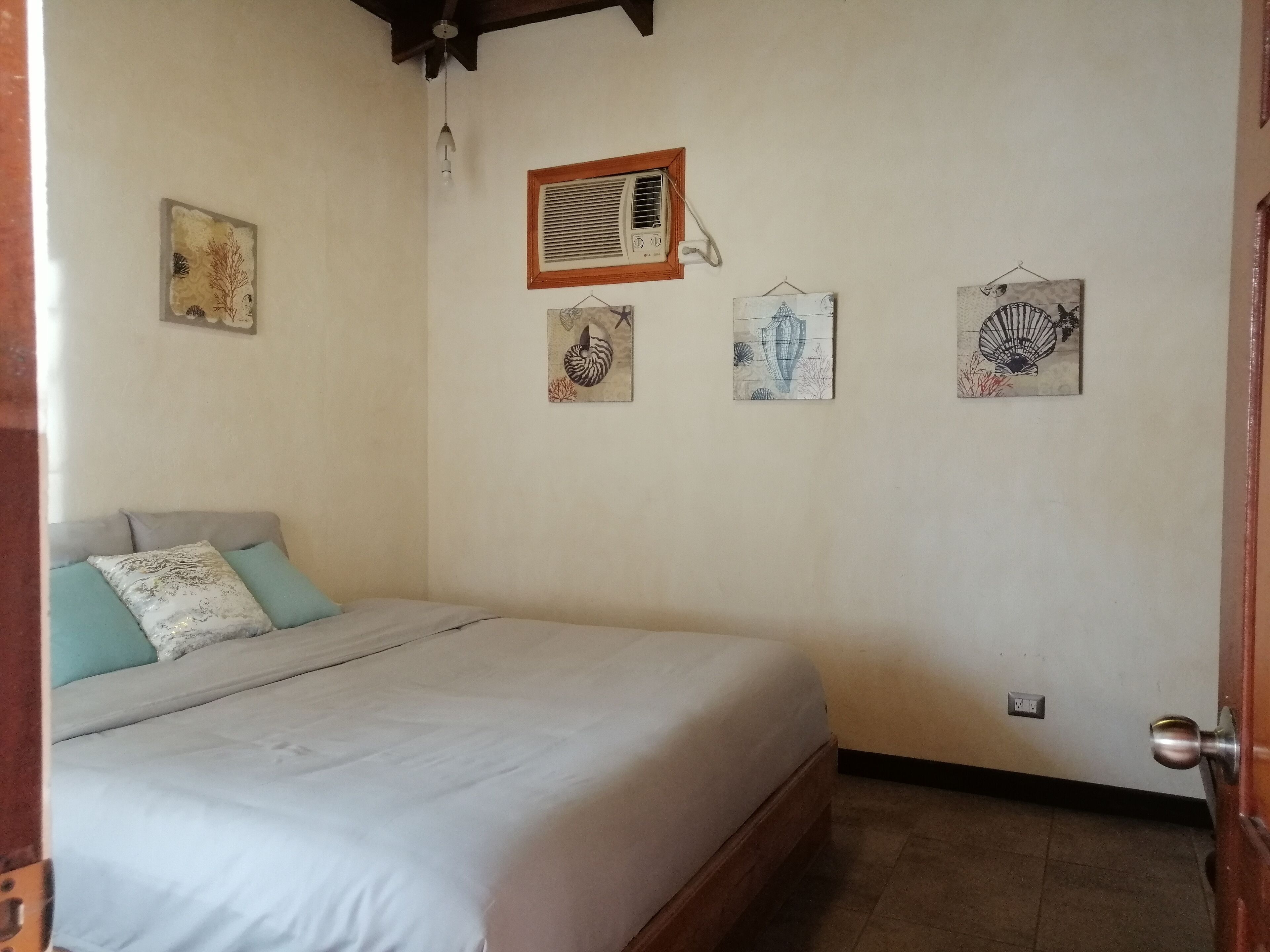 A bedroom with a bed, a radiator, and four wall-mounted artworks.