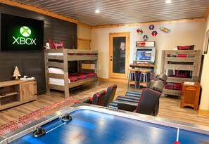 A room with bunk beds, a foosball table, an Xbox console, and a gaming station. - Splashing at the Bluff: Indoor Pool, Theater, Arcade, Hot Tub, Sleeps 22 (Sevier County)