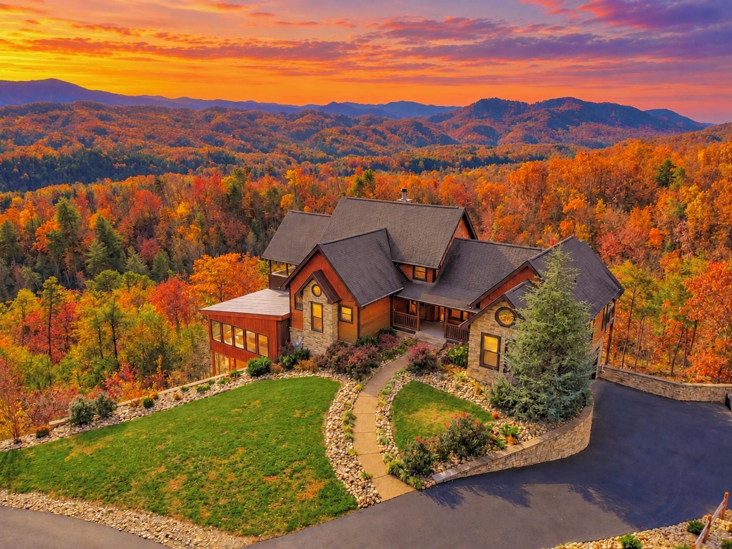 A large house with a stone foundation and multiple roofs, surrounded by a well-maintained lawn and a driveway.