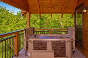 A hot tub on a wooden deck with a view of lush greenery.