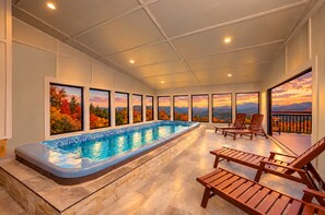 A swimming pool with a view of autumn foliage and mountains through large windows. - Splashing at the Bluff: Indoor Pool, Theater, Arcade, Hot Tub, Sleeps 22 (Sevier County)
