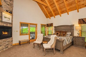 A bedroom with a fireplace, a bed with a wooden headboard, a bench, and a chair. - Splashing at the Bluff: Indoor Pool, Theater, Arcade, Hot Tub, Sleeps 22 (Sevier County)
