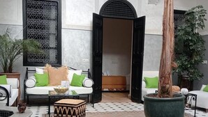 A spacious indoor area with a sofa set, a large planter, and a patterned ottoman. - Riad étoile ocre  (Marrakech)