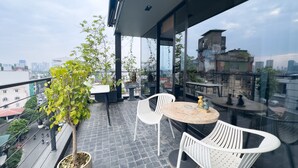 Ein Balkon mit Tisch und Stühlen, Topfpflanzen und Blick auf die Stadt.
