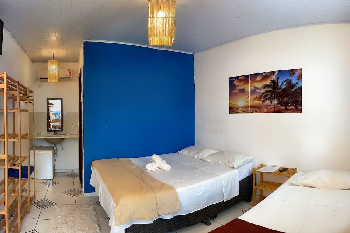 A bedroom with a bed, a desk, a chair, a TV, and a bathroom.