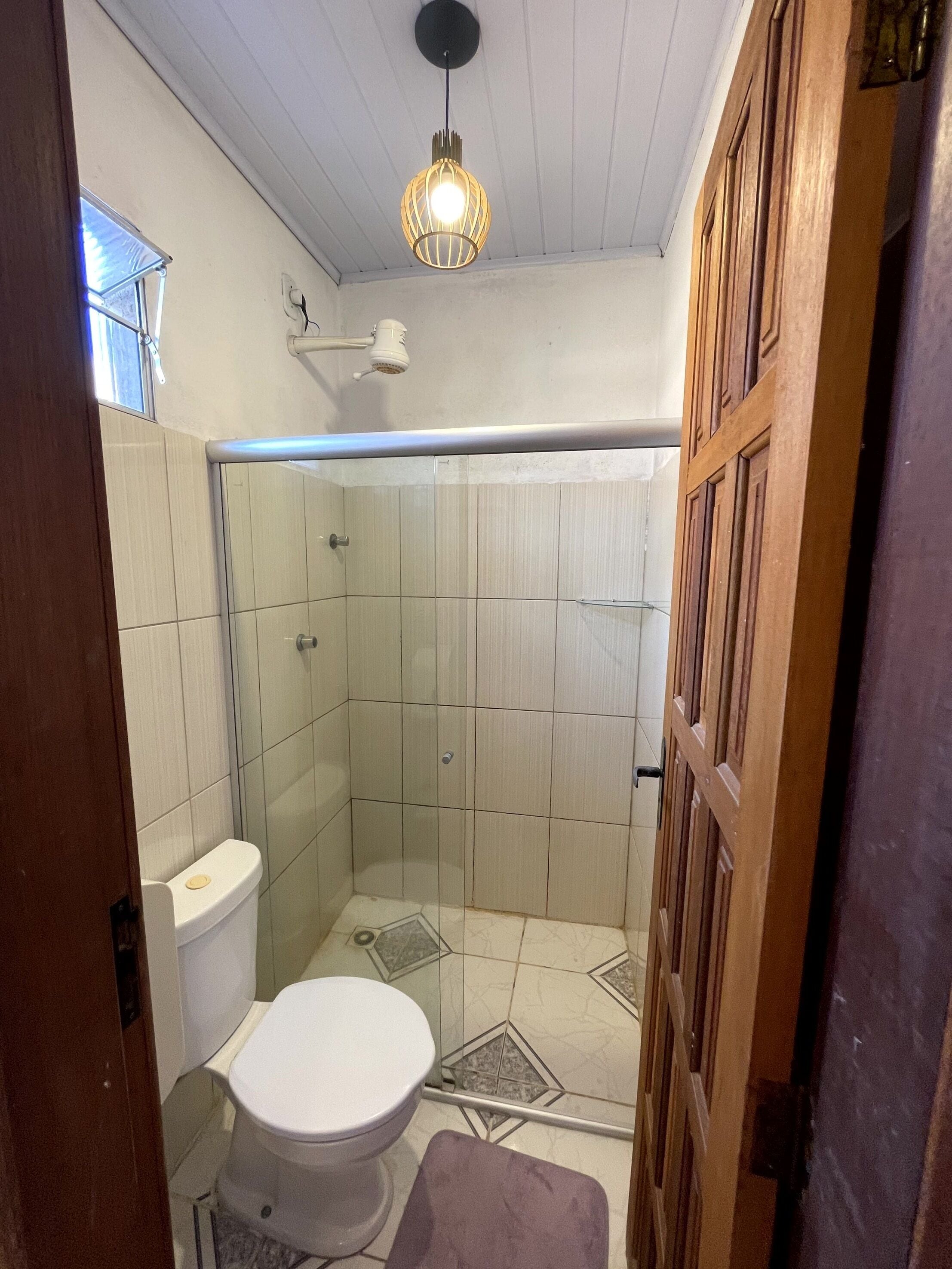 Un baño con inodoro, ducha y una lámpara colgante.