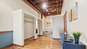 A spacious hallway with wooden flooring, a black reception desk, and a small plant. - Enjoy downtown living with the comforts of home! (Springfield)