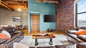 A modern living room with leather sofas, a wooden coffee table, and a brick wall. - Enjoy downtown living with the comforts of home! (Springfield)