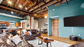 A spacious living area with a leather sofa, a coffee table, and a flat-screen TV mounted on the wall. - Enjoy downtown living with the comforts of home! (Springfield)