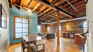 Una habitación amplia con una mesa de comedor de madera, un sofá y una pared de ladrillo.