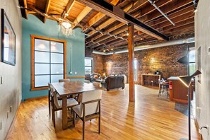 A spacious room with a wooden dining table, a sofa, and a brick wall. - Enjoy downtown living with the comforts of home! (Springfield)