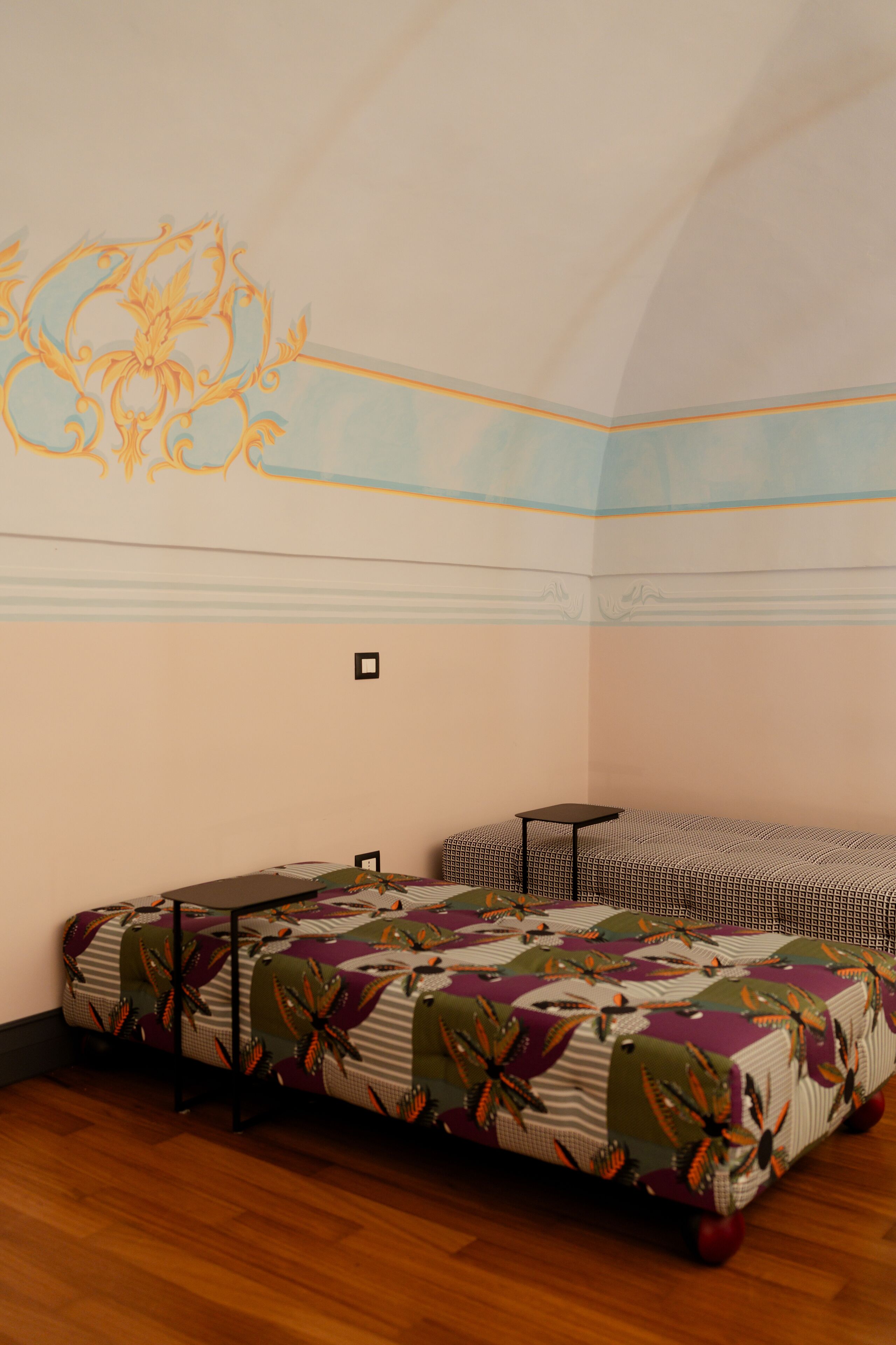 Una habitación con un sofá estampado, una mesita y un diseño decorativo en la pared.