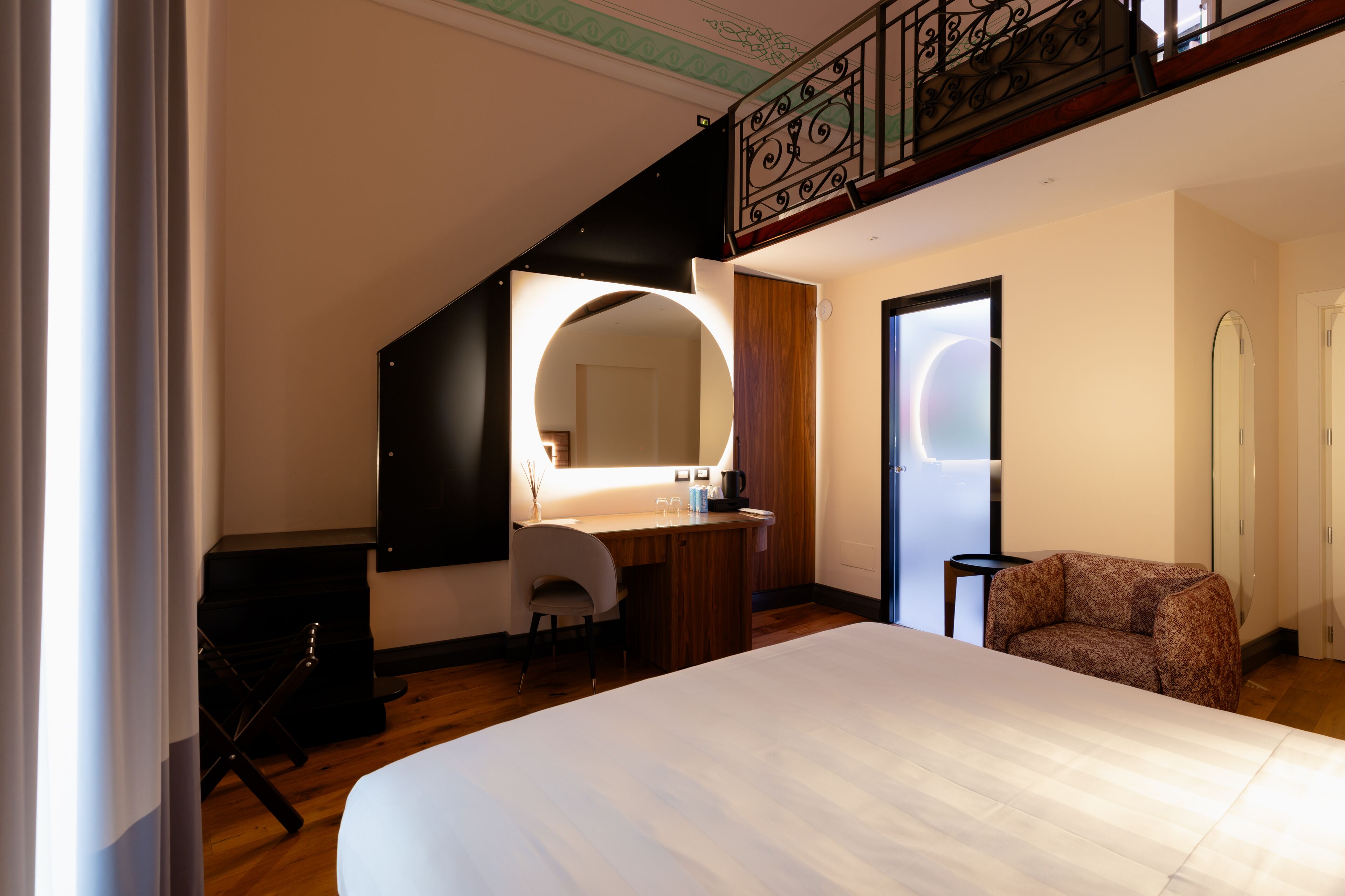 Une chambre à coucher avec un grand lit, un bureau avec une chaise, un miroir et un escalier.