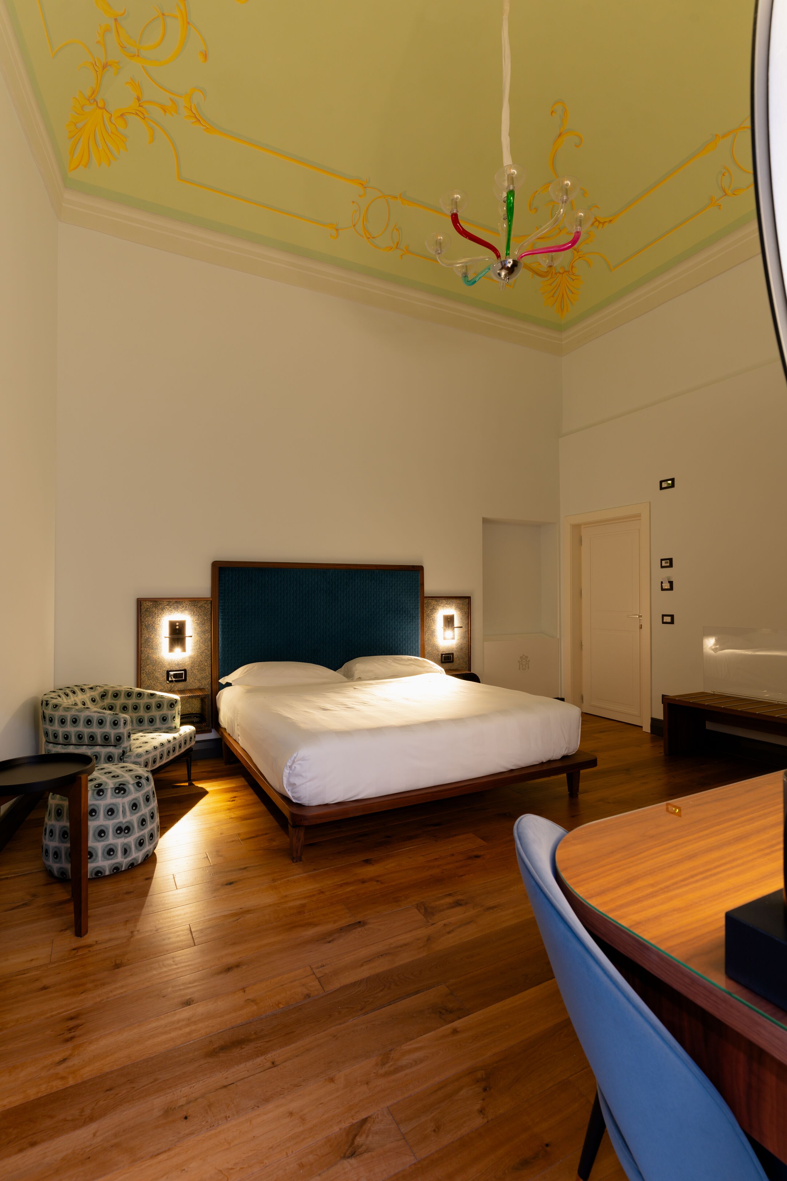 Een hotelkamer met een bed, een bureau, een stoel en een klein tafeltje.