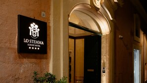 Het uiterlijk van Hotel Lo Stemma Luxury Hotel met een naambord, een gebogen entree en een bloempot.