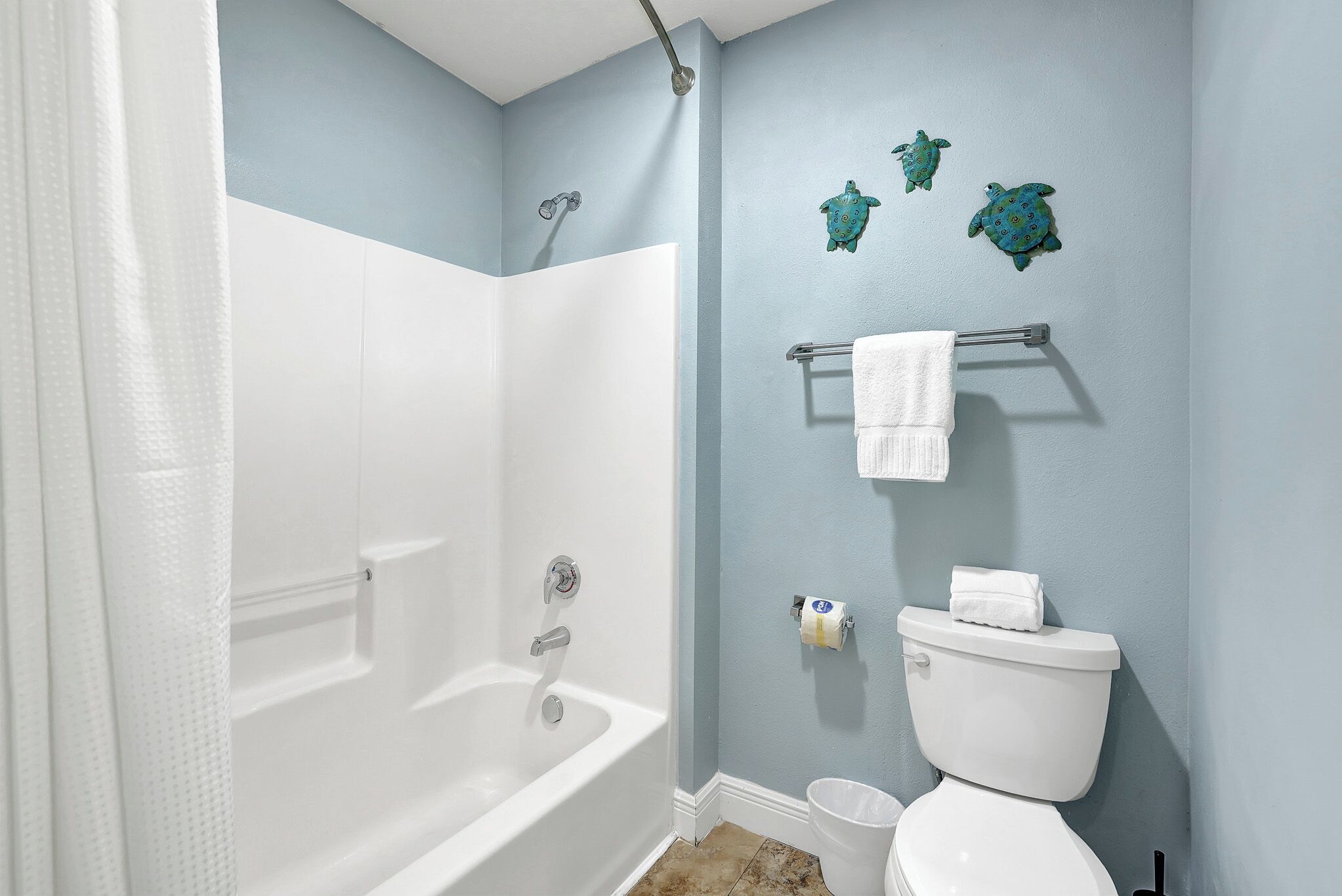 A bathroom with a bathtub, toilet, and towel rack.