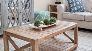 Une table basse en bois sur laquelle est posé un plateau contenant divers objets décoratifs, dans un salon.