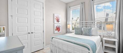 A bedroom with a bed, a ceiling fan, a window with curtains, and a door.
