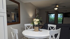 A dining area with a white round table and chairs, a vase with flowers, and a ceiling fan. - NEW condo! Just 15 min to Ft Myers and Sanibel beach! Great Location!! (Fort Myers)