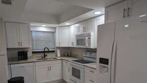 A modern kitchen with white cabinetry, a built-in microwave, an oven, and a refrigerator. - NEW condo! Just 15 min to Ft Myers and Sanibel beach! Great Location!! (Fort Myers)