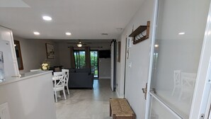 A modern kitchen with a dining area, a hallway with a bench, and a sliding glass door leading to a balcony. - NEW condo! Just 15 min to Ft Myers and Sanibel beach! Great Location!! (Fort Myers)