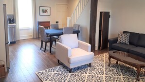 A spacious living room with a dining area, a staircase, and a modern kitchen.