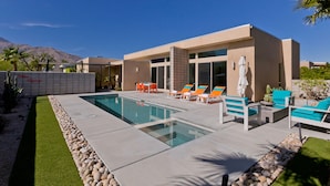 Ein moderner Poolbereich mit rechteckigem Pool, Liegestühlen und einem Patio-Tisch.