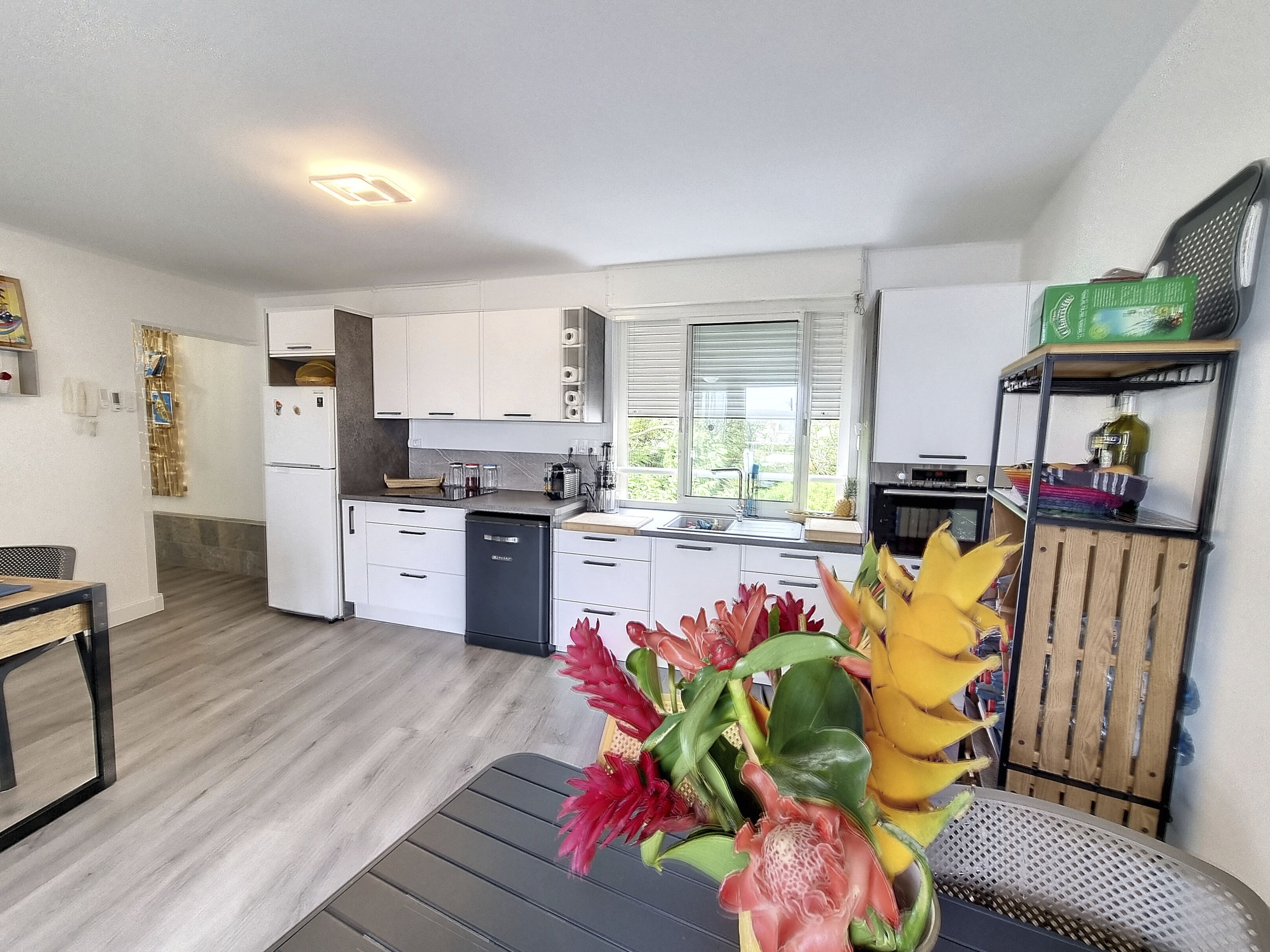 A compact kitchen with white cabinets, a dishwasher, and a window with blinds.