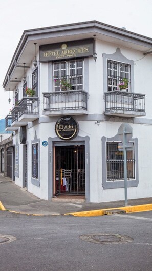 Un immeuble de deux étages, avec une enseigne indiquant « Hôtel Arrecifes » et « El Adri Bar y Restaurante » au rez-de-chaussée.