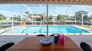 Un área junto a la piscina con una mesa de madera, un cuenco y dos tazas.