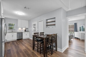 Una cocina moderna con armarios blancos, una mesa de comedor de madera y un horno empotrado.