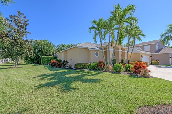 A residential house with a well-maintained lawn, palm trees, and a variety of shrubs. - Paradise Escape Luxury Pool w/Game Room Close to All! Minutes to Beach
(Naples)